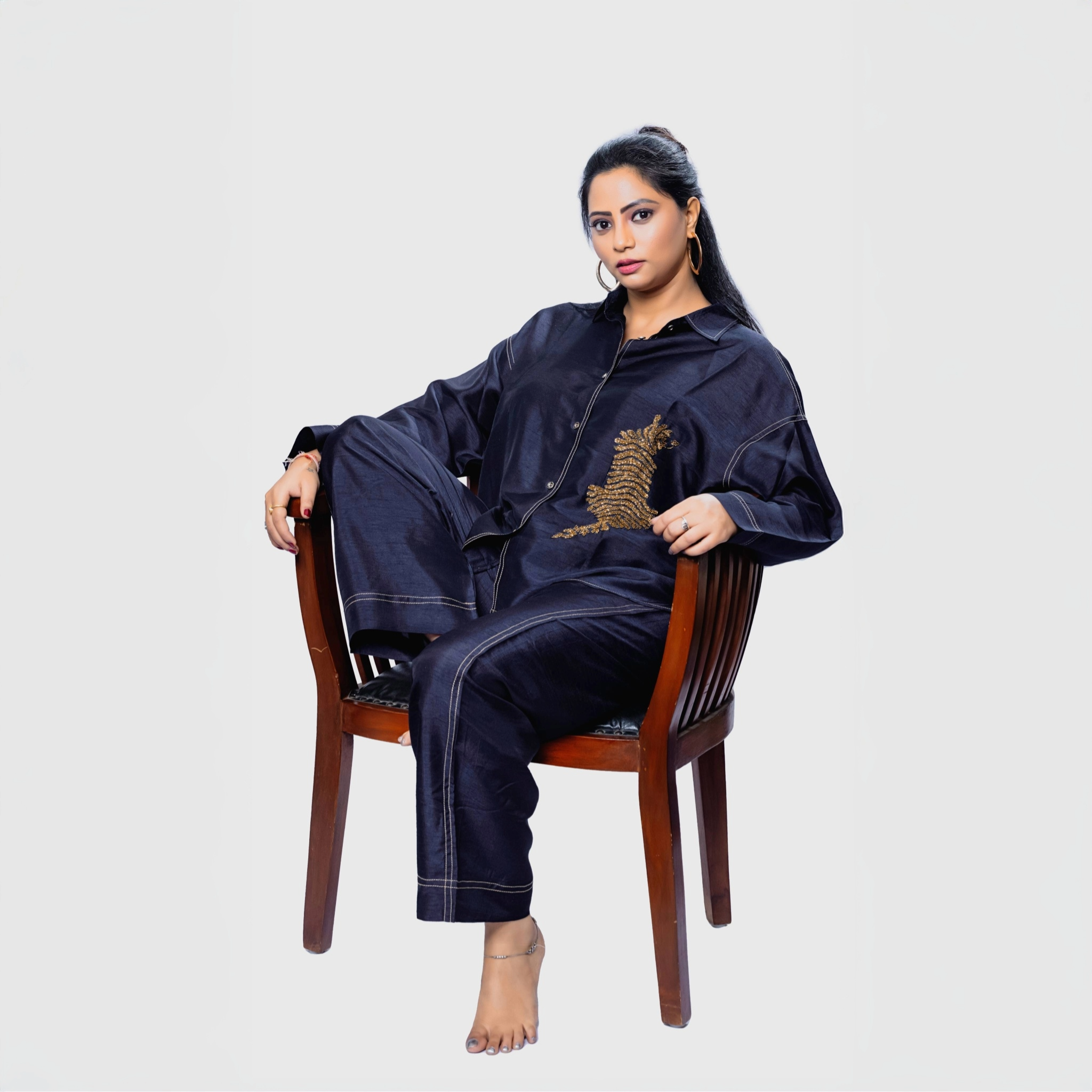Handcrafted designer clothing for women navy shirt and pant set with gold embroidery relaxed fit seated on wooden chair