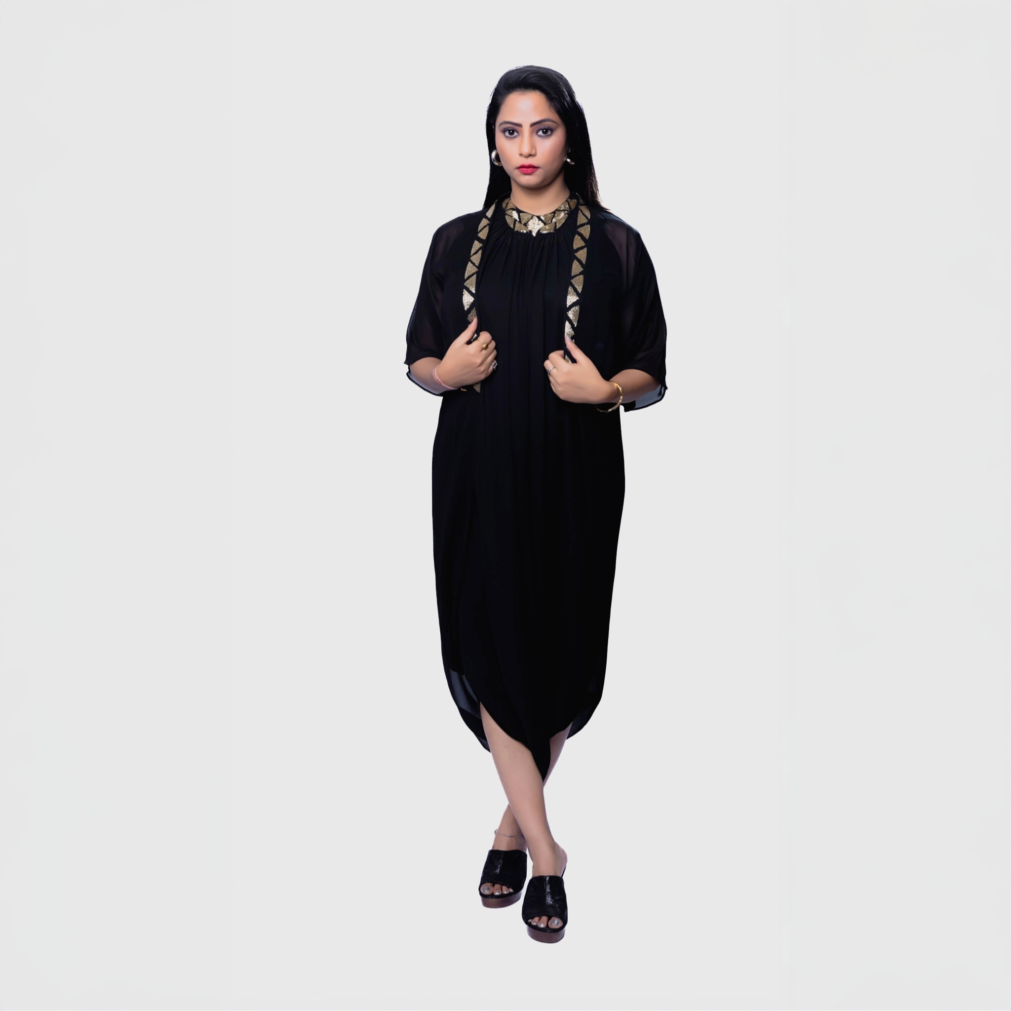 Black cocktail dress with gold embroidery and Jacket worn by woman standing against white background