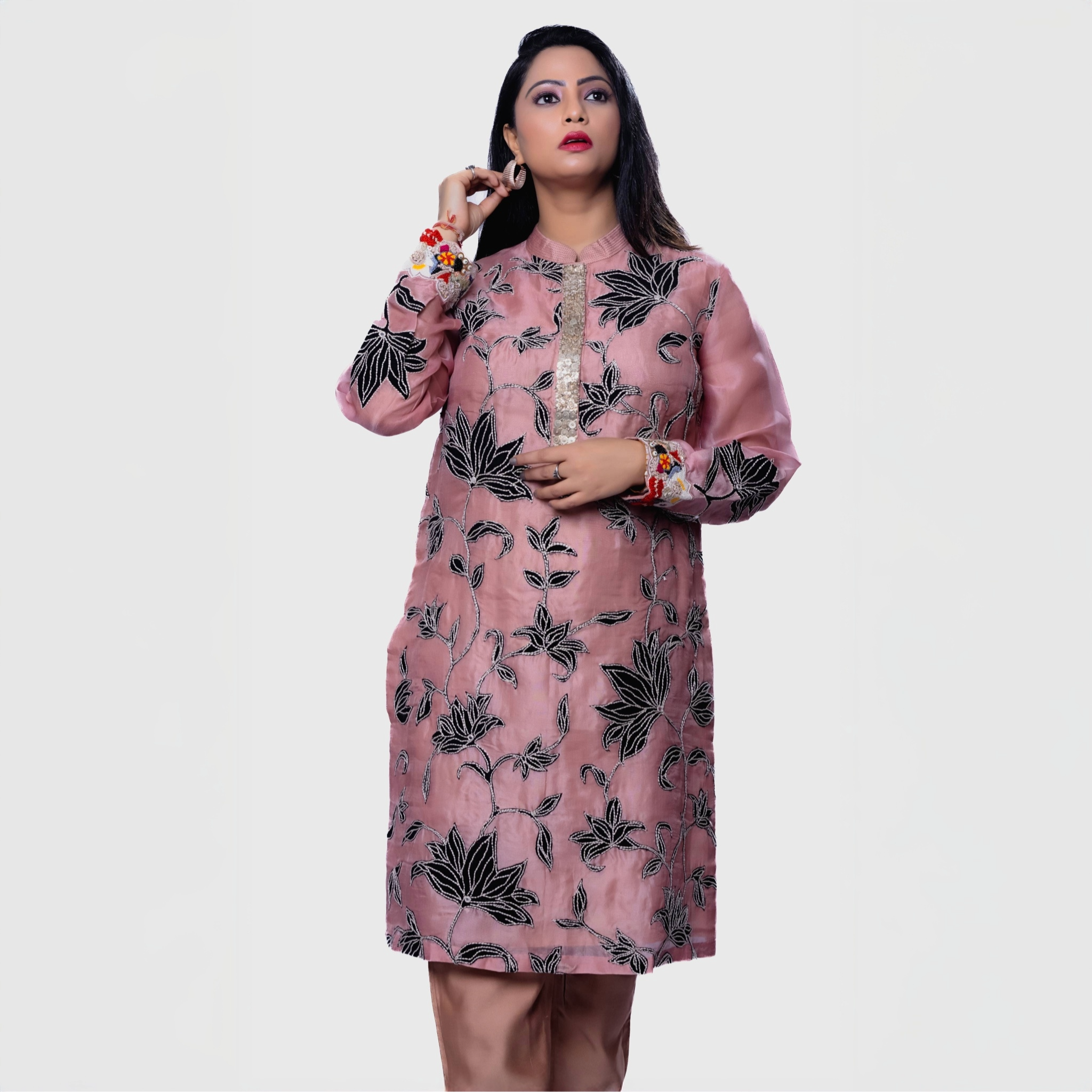 Model wearing a blush floral embroidered kurta set with intricate black leaf designs and vibrant sleeves