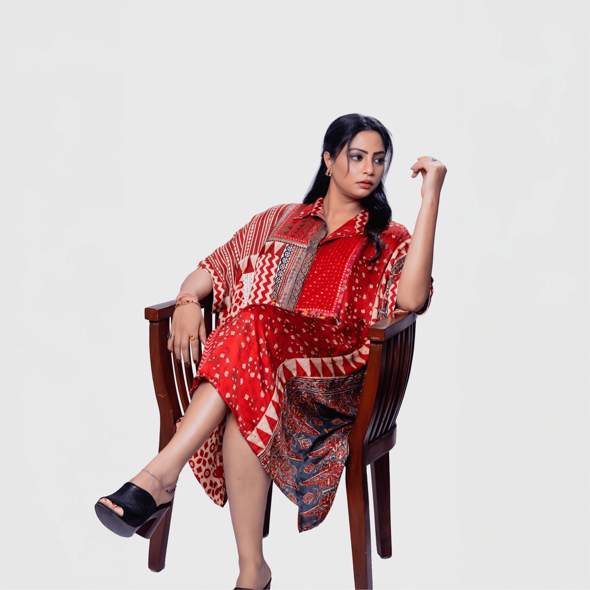 Woman wearing red patterned bohemian chic kaftan outfit sitting on wooden chair