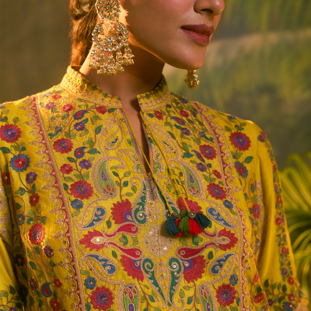 Mustard yellow embroidered kurta set featuring intricate floral designs and stylish tassels