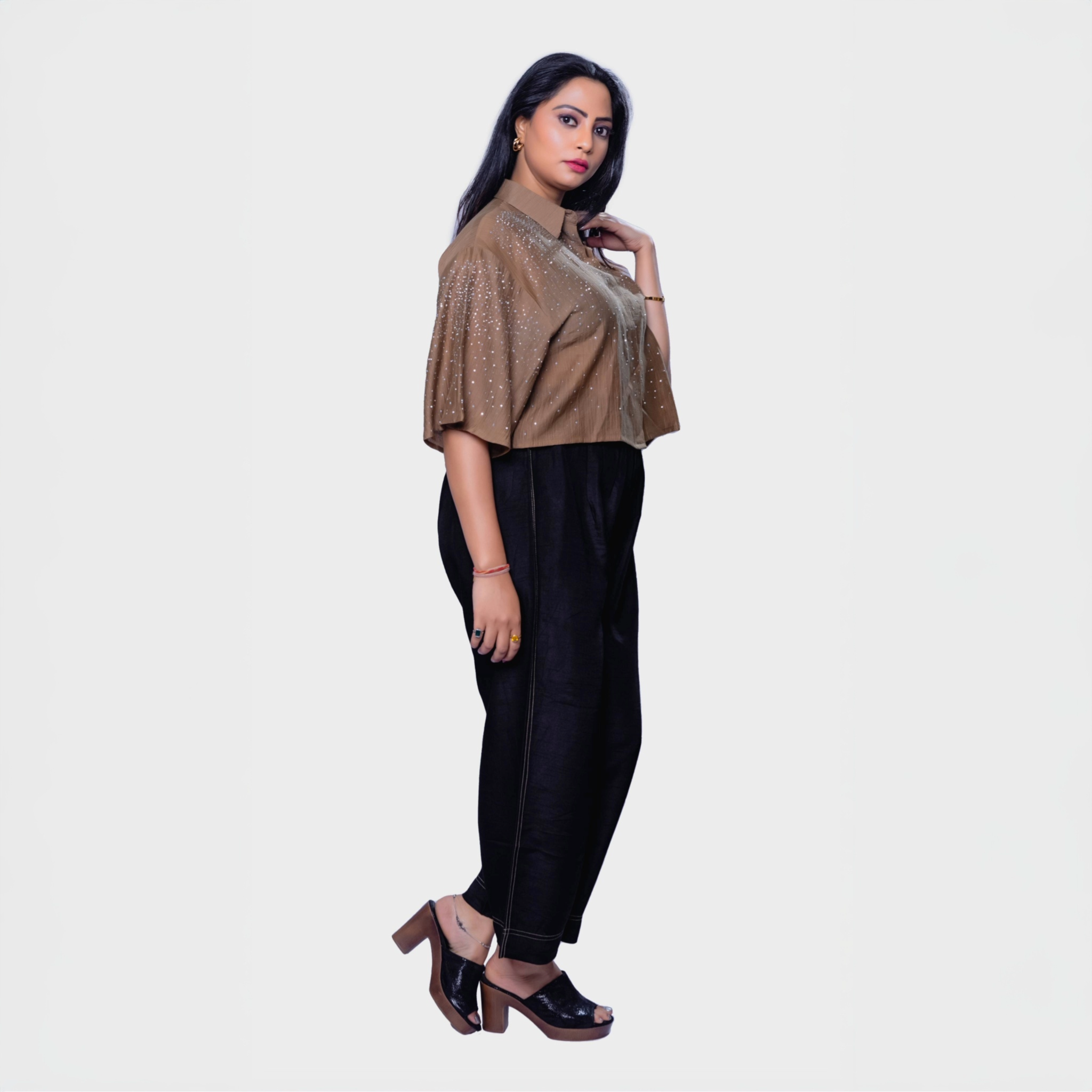 Woman wearing designer shimmering blouse Dubai with brown sequin top and black pants outfit