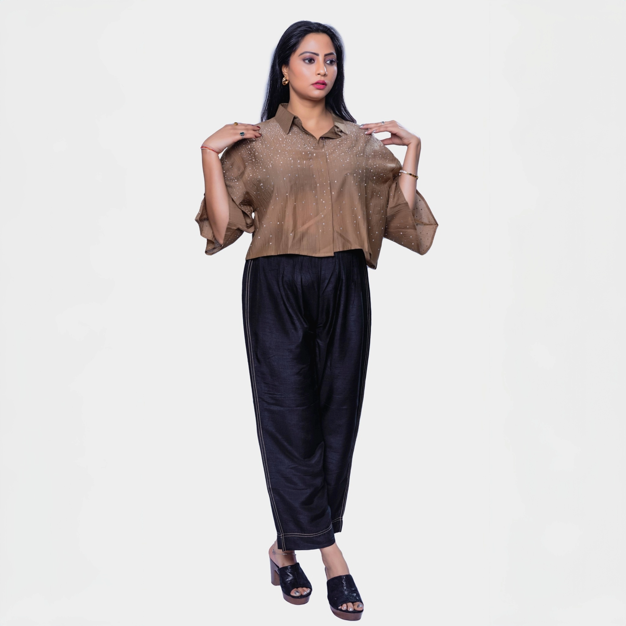 Designer shimmering blouse Dubai in golden color with sparkling sequences, paired with black wide-leg pants
