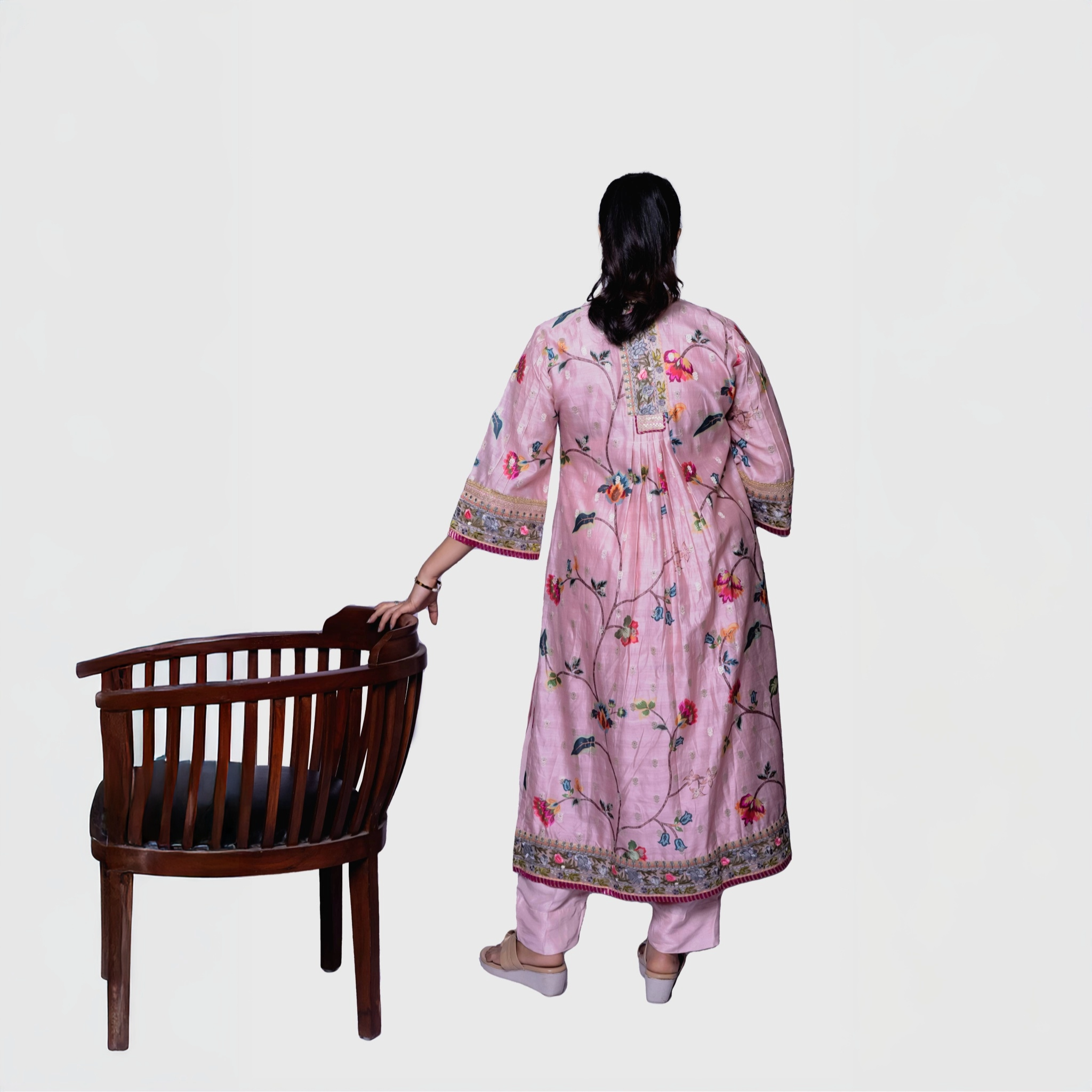 Back view pink salwar kameez set with embroidered floral border and matching pants next to wooden chair luxury floral ethnic wear