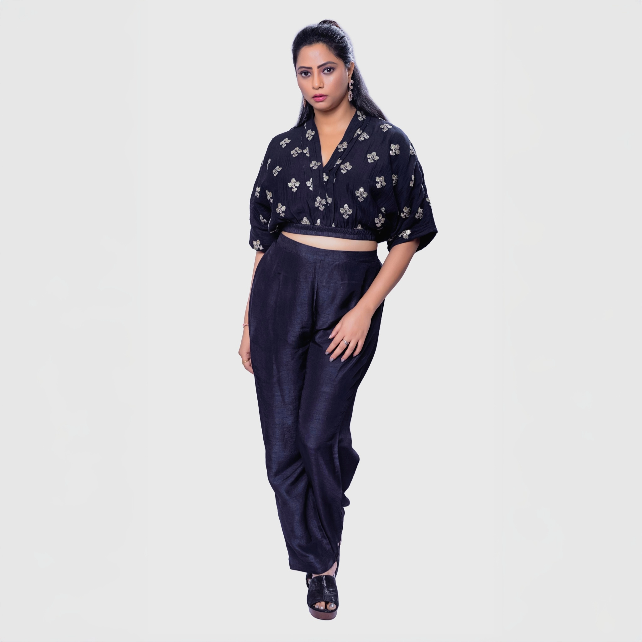 Woman wearing a handcrafted black co-ord outfit with embroidery featuring a cropped top and matching pants