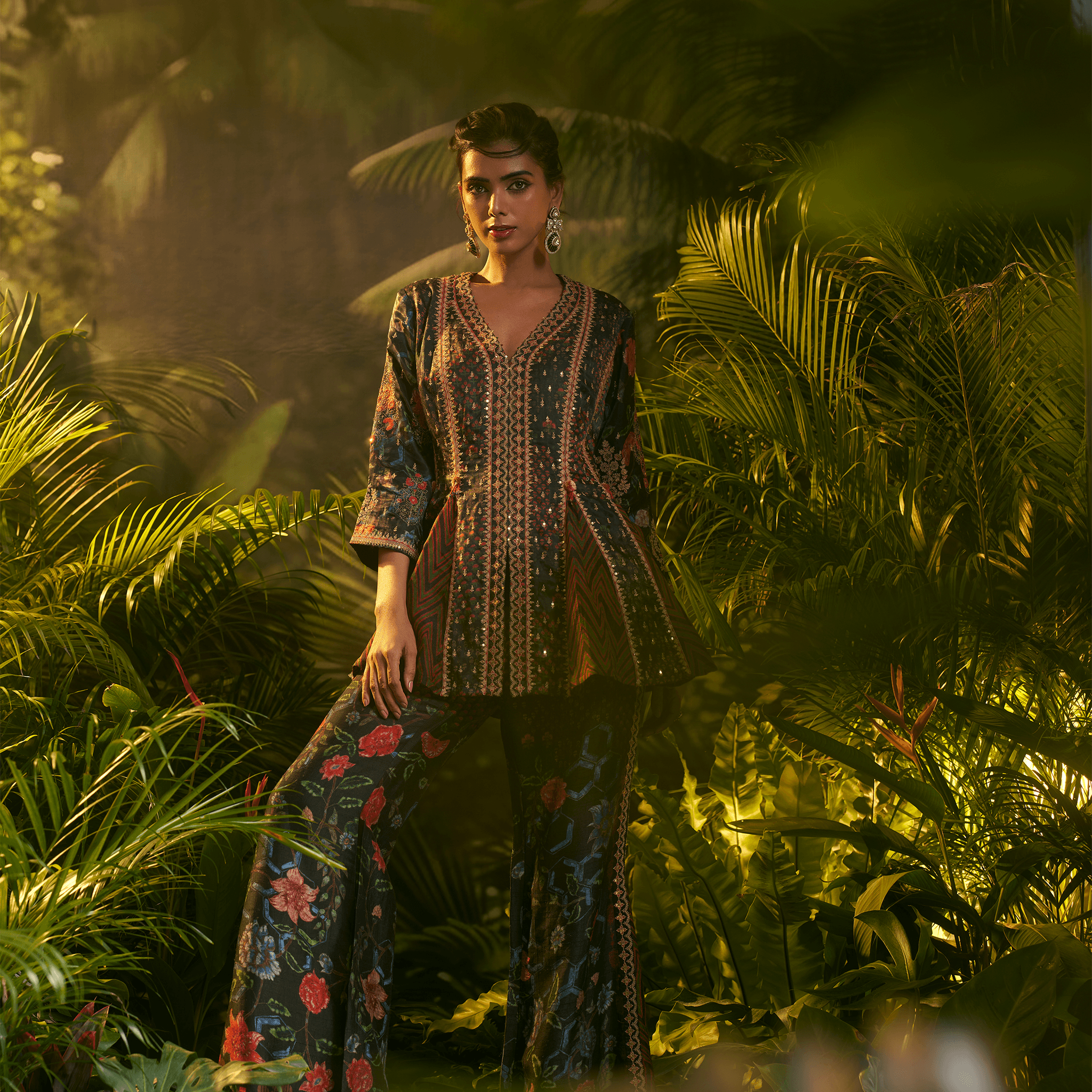 Model wearing a midnight bloom peplum ensemble with vibrant colors and intricate patterns in a lush setting