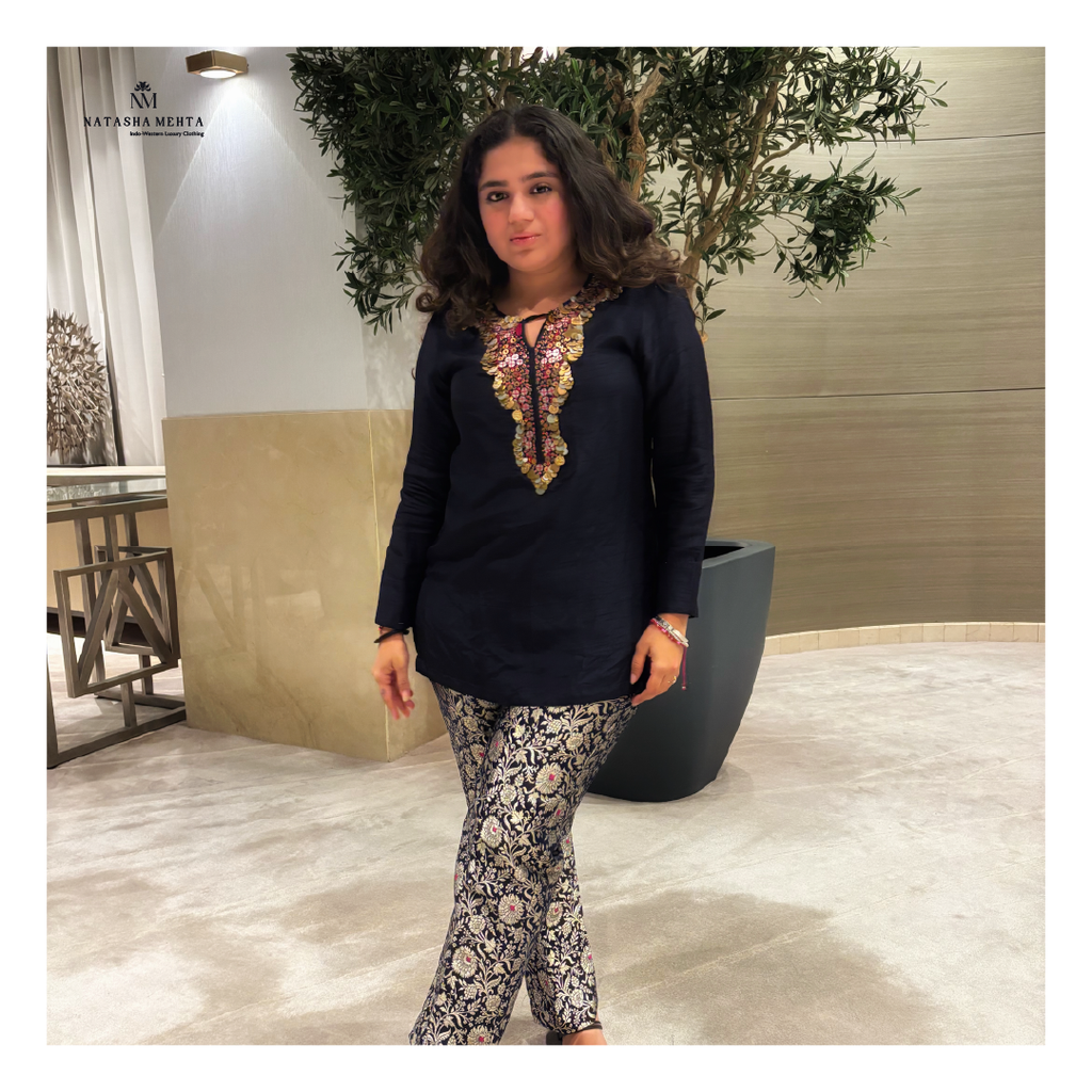 Woman in navy blue tunic with embroidered neckline paired with floral pants from midnight elegance womens clothing