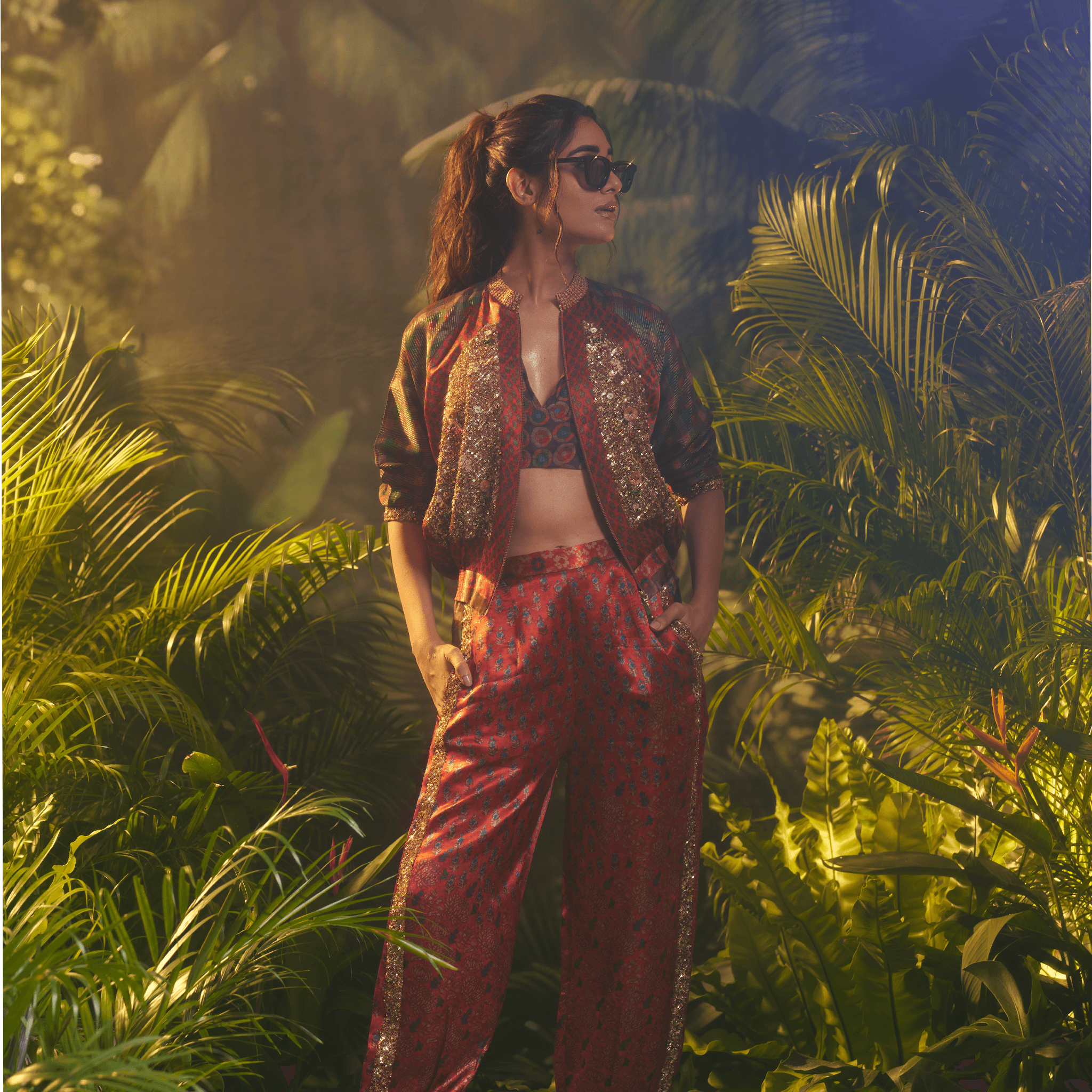 Stylish women's statement bomber jacket India with floral design paired with matching pants in a tropical setting